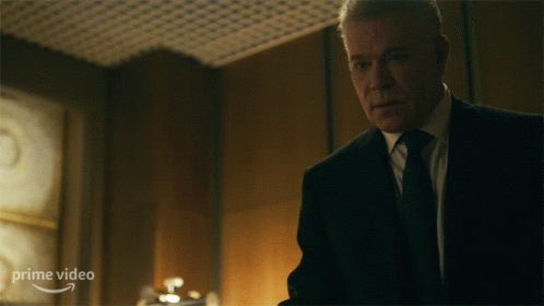 A Man In A Suit And Tie Is Standing In Front Of A Sign That Says Prime Video On It GIF