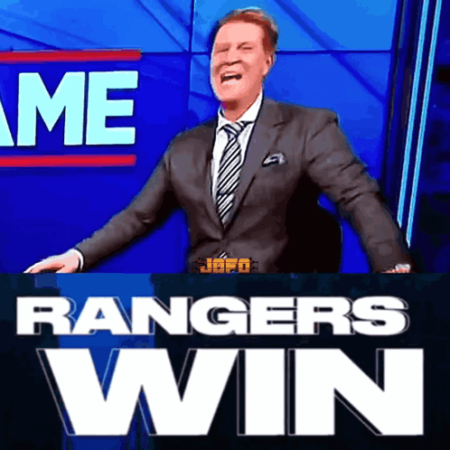 A Man In A Suit And Tie Is Standing In Front Of A Sign That Says " Rangers Win " GIF