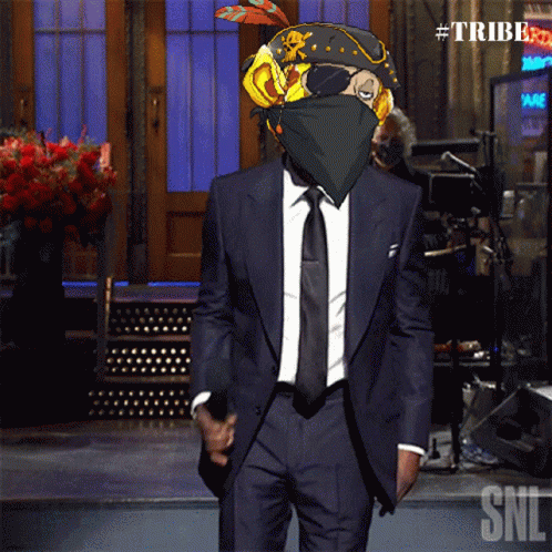 A Man In A Suit And Tie Is Standing In Front Of A Sign That Says Tribe GIF
