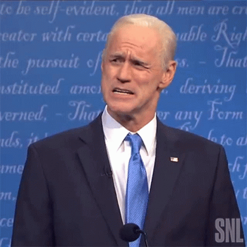 A Man In A Suit And Tie Is Standing In Front Of A Snl Sign GIF