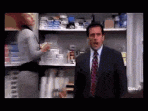 A Man In A Suit And Tie Is Standing In Front Of A Store Shelf . GIF