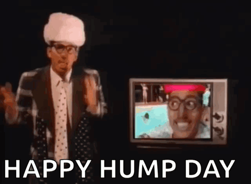 A Man In A Suit And Tie Is Standing In Front Of A Television And Waving His Hand . GIF
