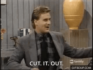 A Man In A Suit And Tie Is Standing In Front Of A Vase . GIF