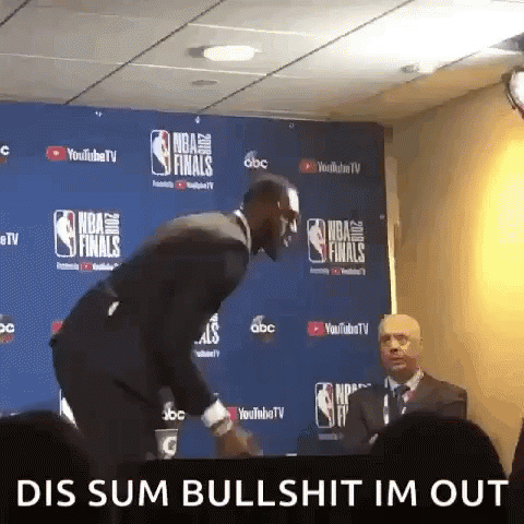 a man in a suit and tie is standing in front of a wall that says nba finals
