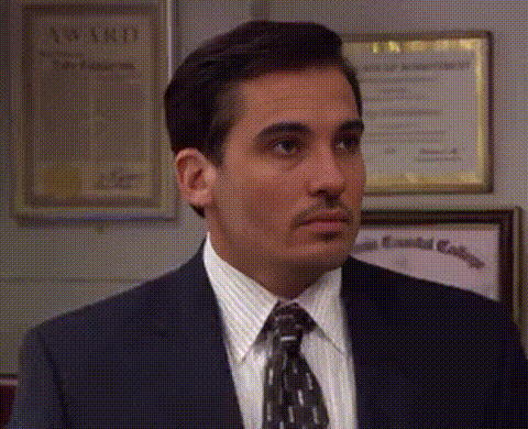A Man In A Suit And Tie Is Standing In Front Of A Wall With A Certificate Hanging On It . GIF