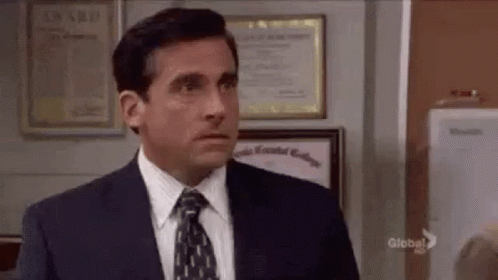 A Man In A Suit And Tie Is Standing In Front Of A Wall With A Certificate On It . GIF