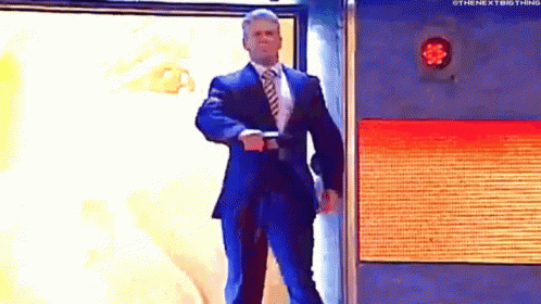 A Man In A Suit And Tie Is Standing In Front Of A Wall With A Red Light On It . GIF