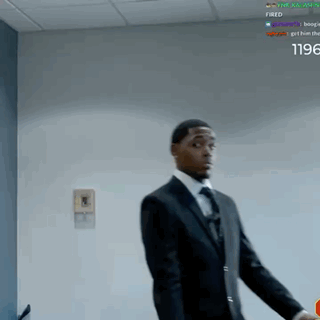 A Man In A Suit And Tie Is Standing In Front Of A Wall With The Words Fired On It GIF