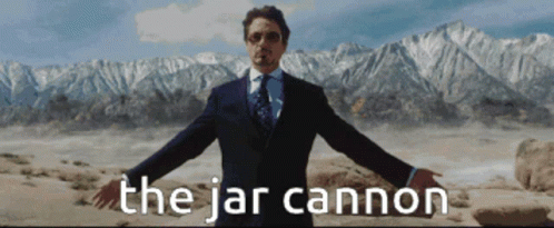 A Man In A Suit And Tie Is Standing In Front Of Mountains And The Words The Jar Cannon GIF