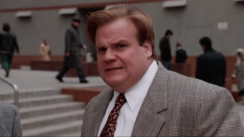 A Man In A Suit And Tie Is Standing In Front Of Stairs GIF