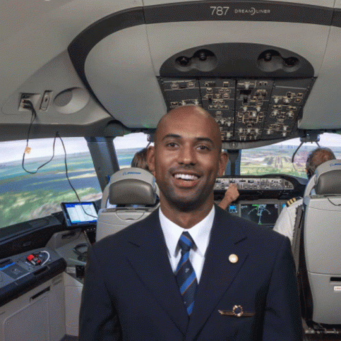 A Man In A Suit And Tie Is Standing In The Cockpit Of A 787 Dreamliner GIF