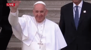 A Man In A Suit And Tie Is Standing Next To A Man In A White Robe Who Is Waving . GIF