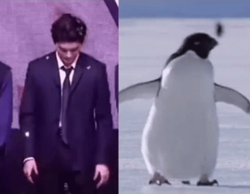 A Man In A Suit And Tie Is Standing Next To A Penguin On The Snow . GIF