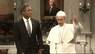 A Man In A Suit And Tie Is Standing Next To A Pope In A Room . GIF