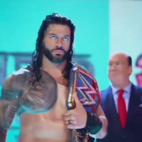 A Man In A Suit And Tie Is Standing Next To A Shirtless Wrestler Holding A Wrestling Championship Belt GIF