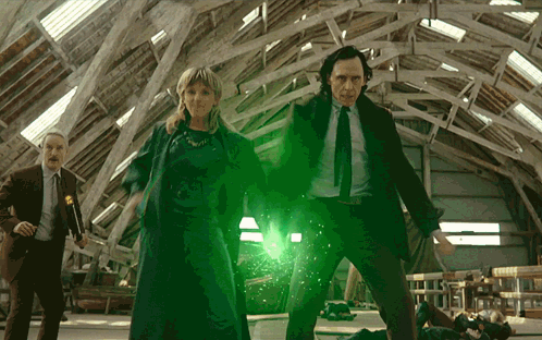 A Man In A Suit And Tie Is Standing Next To A Woman And A Man In A Suit GIF