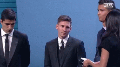 A Man In A Suit And Tie Is Standing Next To A Woman Holding A Microphone While Two Other Men Stand Behind Him . GIF