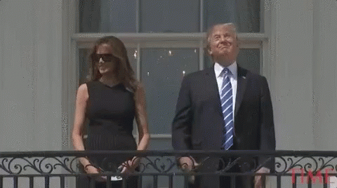 A Man In A Suit And Tie Is Standing Next To A Woman In A Black Dress . GIF