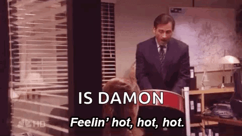 A Man In A Suit And Tie Is Standing Next To A Woman In A Chair And Talking To Her . GIF