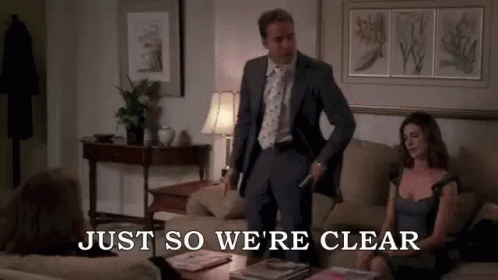 A Man In A Suit And Tie Is Standing Next To A Woman On A Couch In A Living Room . GIF