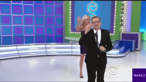 A Man In A Suit And Tie Is Standing Next To A Woman On A Stage With A Yahoo Logo In The Corner GIF