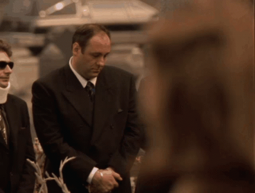A Man In A Suit And Tie Is Standing Next To A Woman GIF