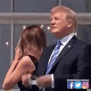 A Man In A Suit And Tie Is Standing Next To A Woman Who Is Covering Her Face . GIF