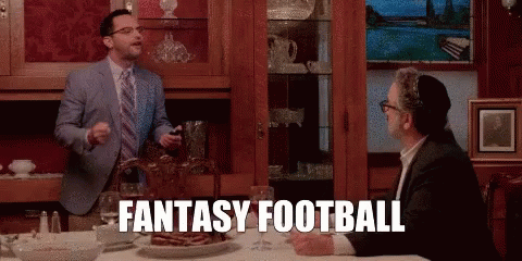 A Man In A Suit And Tie Is Standing Next To Another Man At A Table And Says Fantasy Football . GIF