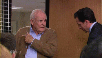 A Man In A Suit And Tie Is Standing Next To Another Man In A Sweater . GIF