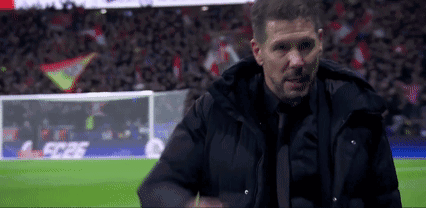 A Man In A Suit And Tie Is Standing On A Soccer Field With A Crowd In The Background . GIF