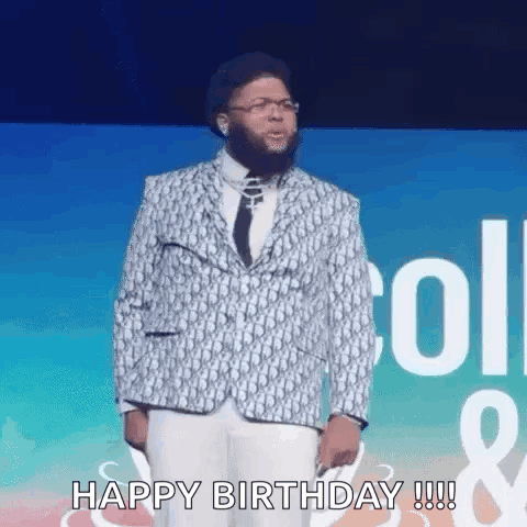 A Man In A Suit And Tie Is Standing On A Stage And Says `` Happy Birthday '' . GIF