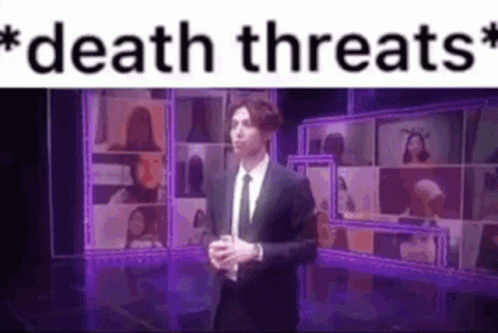 A Man In A Suit And Tie Is Standing On A Stage In Front Of A Purple Screen . GIF