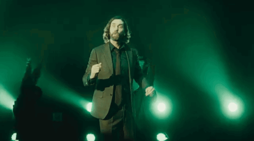 Man In Suit And Tie With Outstretched Arms On Stage GIF