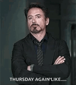 A Man In A Suit And Tie Is Standing With His Arms Crossed And A Beard . GIF