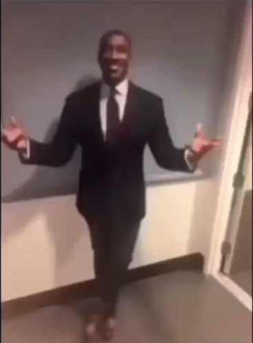 A Man In A Suit And Tie Is Standing With His Arms Outstretched . GIF