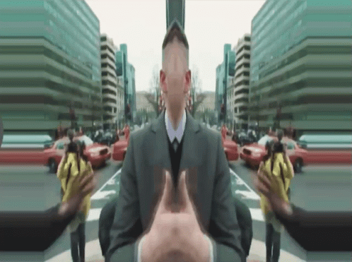 A Man In A Suit And Tie Is Surrounded By Buildings GIF
