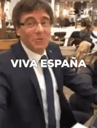 A Man In A Suit And Tie Is Taking A Selfie With The Words Viva Espana On The Bottom . GIF