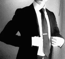 A Man In A Suit And Tie Is Taking Off His Jacket . GIF