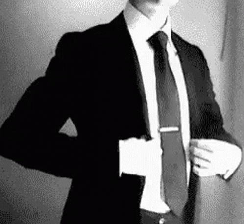 A Man In A Suit And Tie Is Taking Off His Jacket . GIF