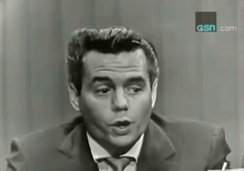 a man in a suit and tie is talking in front of a sign that says gsn.com