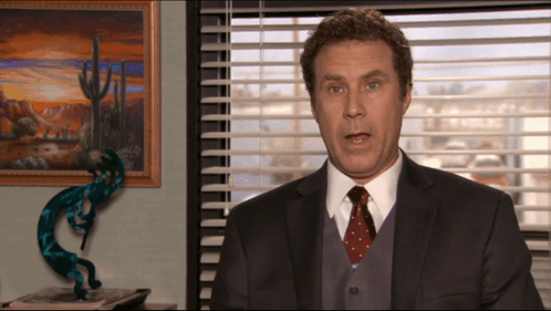 A Man In A Suit And Tie Is Talking In Front Of A Window GIF