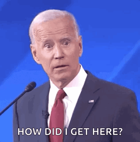 A Man In A Suit And Tie Is Talking Into A Microphone And Says How Did I Get Here GIF