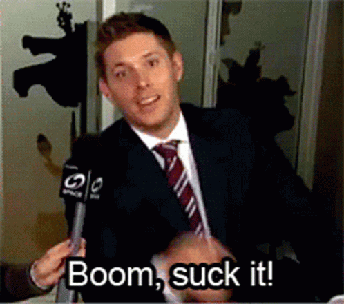 A Man In A Suit And Tie Is Talking Into A Microphone With The Words Boom Suck It Below Him GIF