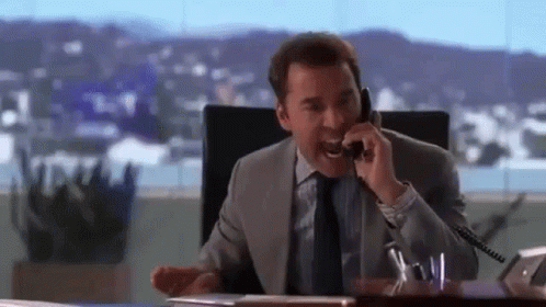 A Man In A Suit And Tie Is Talking On A Cell Phone . GIF
