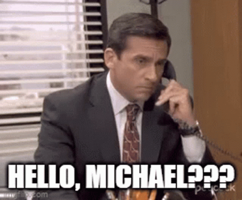 A Man In A Suit And Tie Is Talking On A Phone And Saying `` Hello , Michael ? '' . GIF