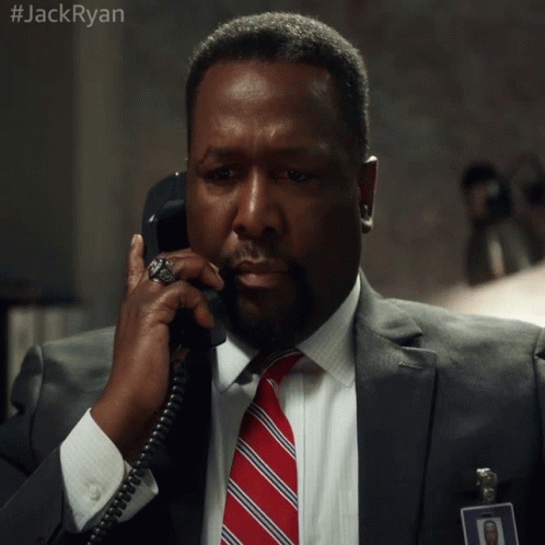 A Man In A Suit And Tie Is Talking On A Phone With #Jackryan Written On The Bottom GIF