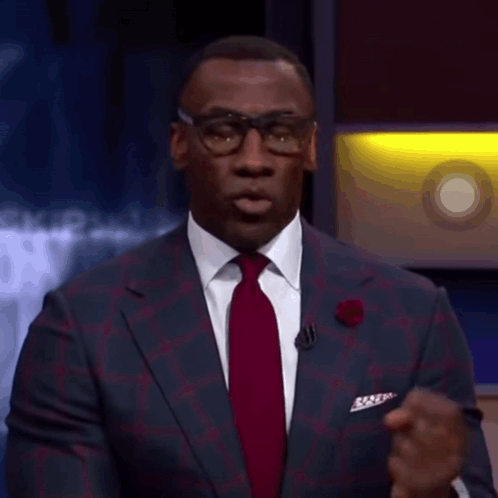 A Man In A Suit And Tie Is Talking On A Stage GIF