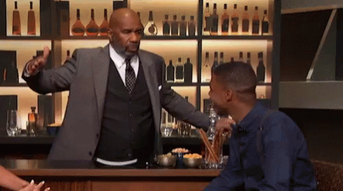 A Man In A Suit And Tie Is Talking To A Man In A Blue Shirt GIF