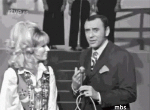 A Man In A Suit And Tie Is Talking To A Woman In A Black And White Photo . GIF