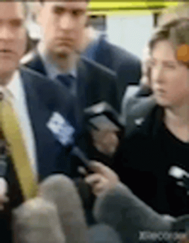 A Man In A Suit And Tie Is Talking To A Woman In A Black Dress . GIF
